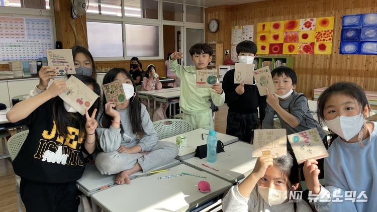 진주대곡초등학교 3학년 학생들과 '꿀벌의 노래'팀이 11월초부터 2주간 동안 교실에서 꿀벌의 소중함에 대한 생태교육을 진행한 뒤 폐박스 종이에 '멸종 위기에 내몰린 공룡과 꿀벌'의 이야기를 담은 후 환하게 웃고 있다./사진='꿀벌의노래'팀