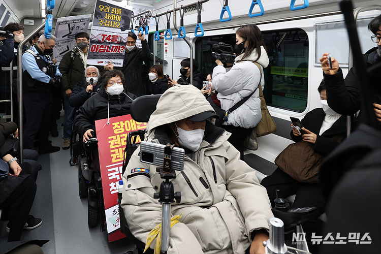 전국장애인차별철폐연대(전장연) 회원들이 12일 서울 용산구 삼각지역 4호선 승강장 앞에서 서울시의 무정차 통과 방안 검토를 규탄하며 장애인 권리 예산 확보를 위한 지하철 타기 선전전을 마친 후 지하철로 이동하고 있다. ⓒ정의철 기자