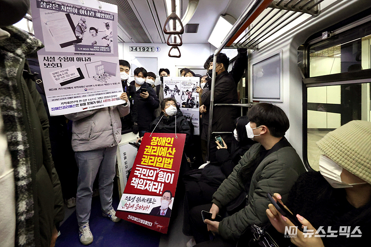 전국장애인차별철폐연대(전장연) 회원들이 12일 서울 용산구 삼각지역 4호선 승강장 앞에서 서울시의 무정차 통과 방안 검토를 규탄하며 장애인 권리 예산 확보를 위한 지하철 타기 선전전을 마친 후 지하철로 이동하고 있다. ⓒ정의철 기자