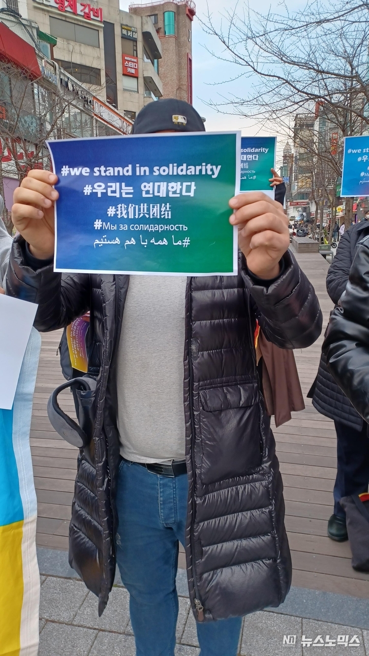 세계 인권의 날(10일)을 맞아 서울 신촌에서 열린 집회 현장에 한 외국인이 '우리는 연대한다'란 문구가 적힌 종이를 들고 시위를 하고 있다.